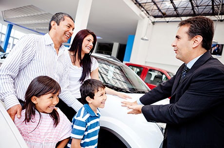 Family meeting with car dealership representative in showroom